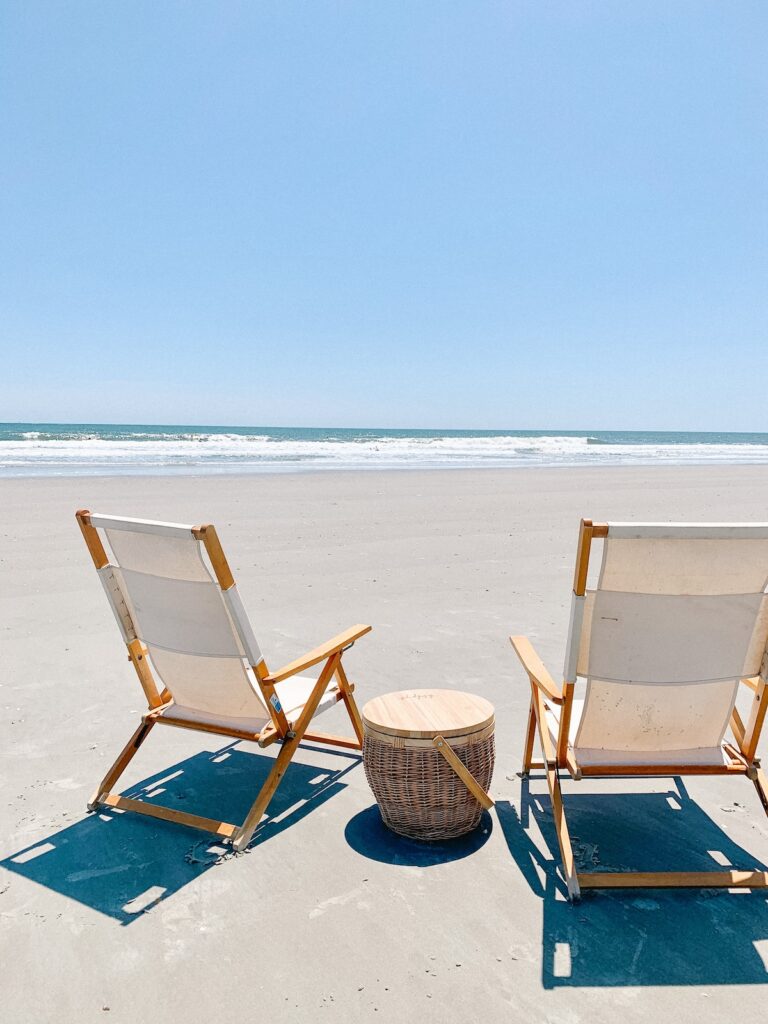 two beach chais and picnic basket on folly beach on a calm, clear day.
