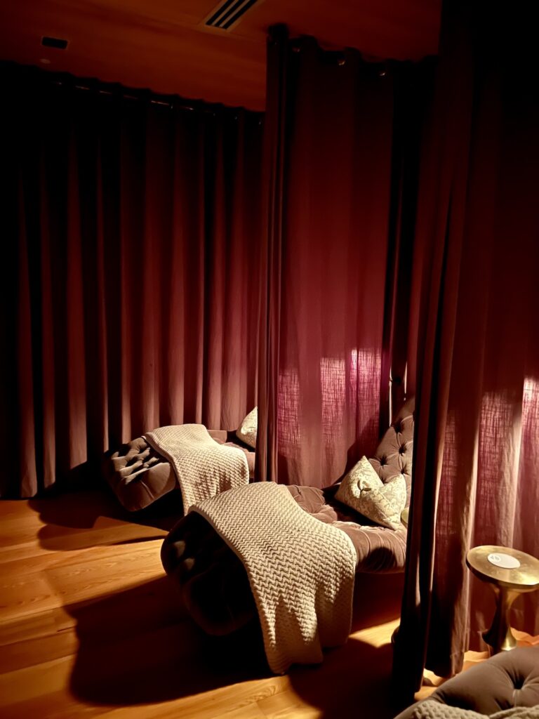 Relaxation room at the Dewberry Hotel with lounge chairs, blankets and pillows for a cozy, dark atmosphere.