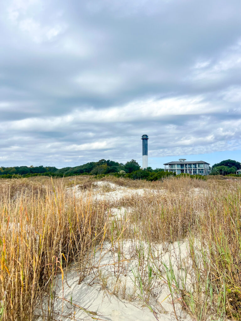 sullivan's island lighthouse seen from the beach with golden dunes in the foreground. It's one of the best beaches in Charleston, South Carolina.